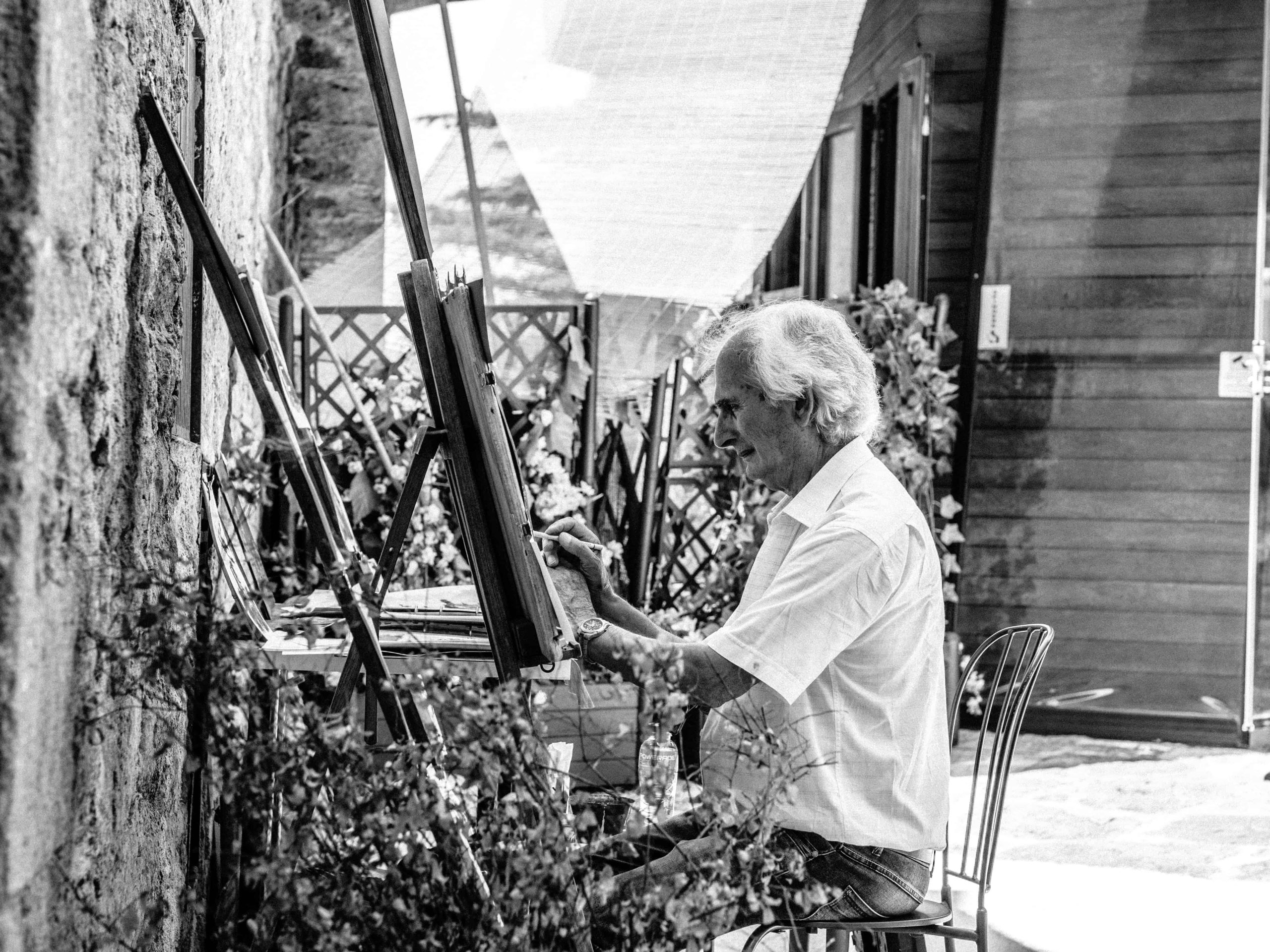 old man painting on canvass