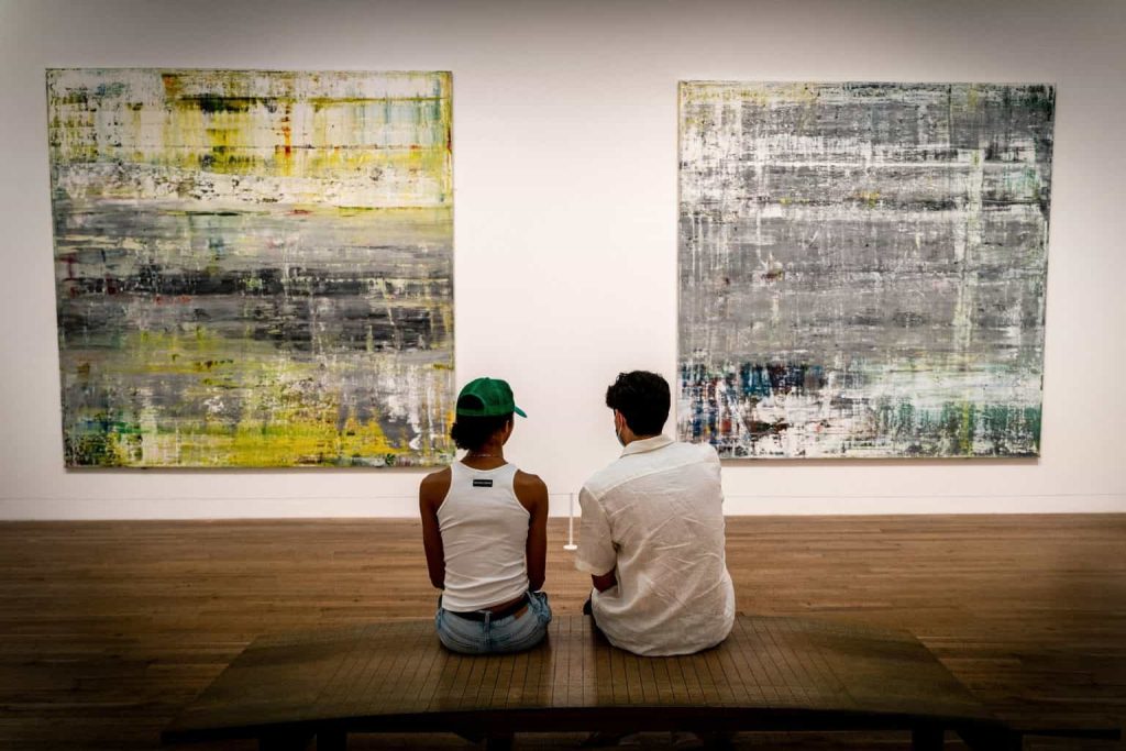 girl and boy sitting in front of paintings