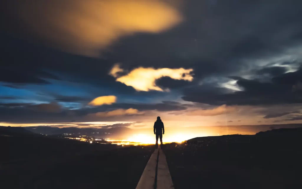 silhouette-man-standing-road-facing-sunset